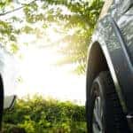 Low angle view of two vehicles' tires facing a sunlit field