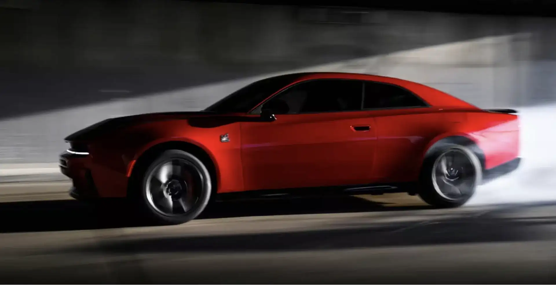 Red Dodge Charger in motion through a tunnel, side profile view.