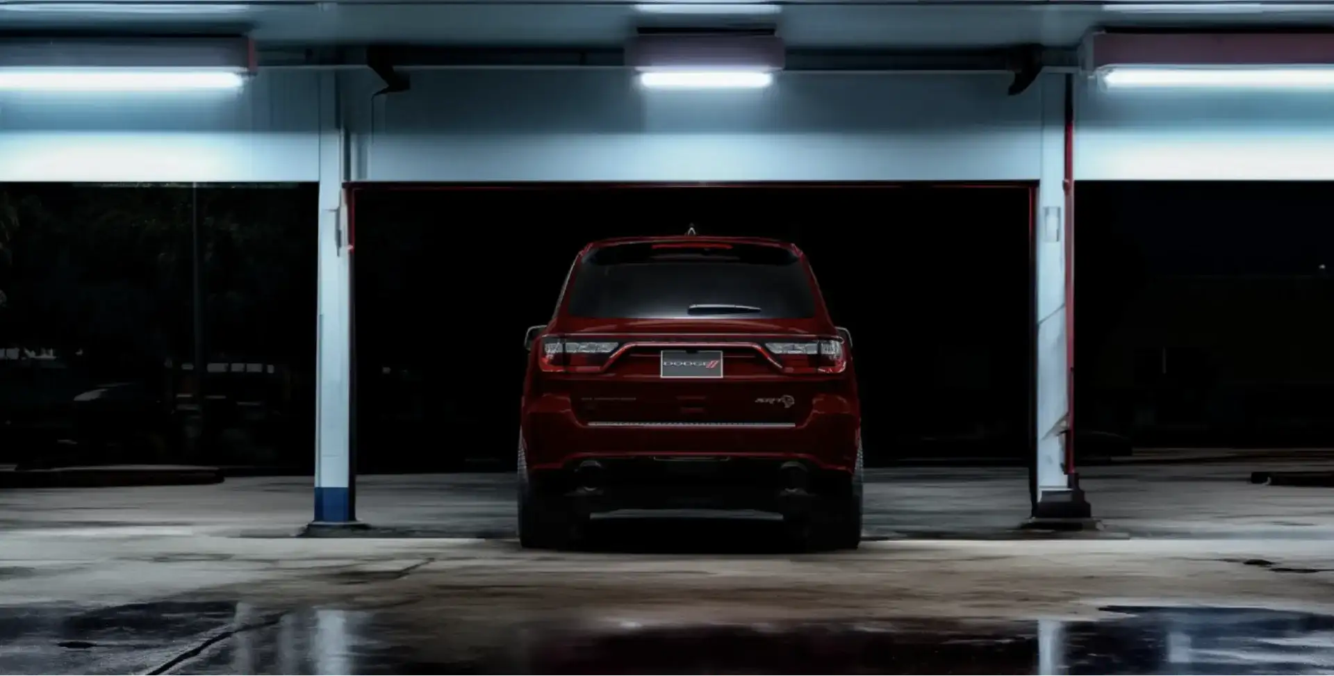 Red Dodge Durango SRT parked in a dimly lit garage, rear view