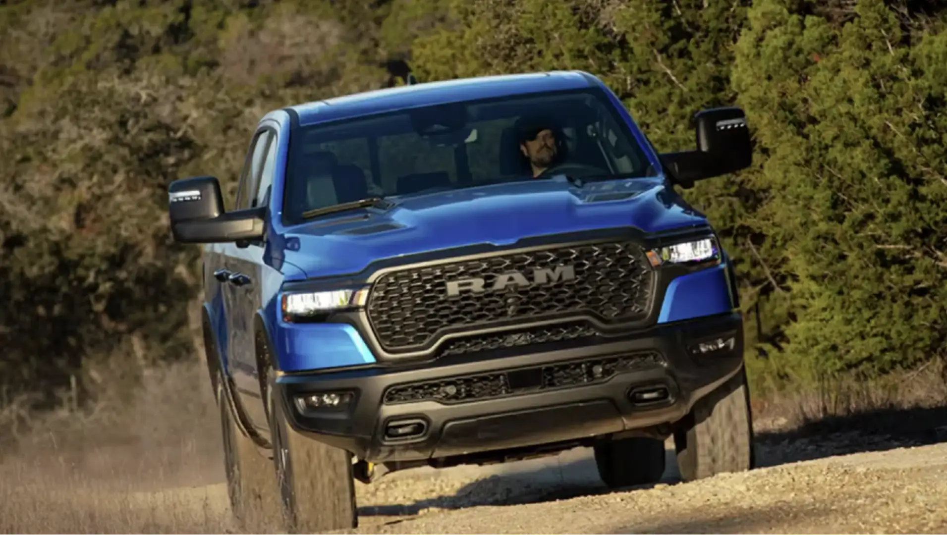 Ram 1500 pickup truck driving down a dirt road with trees in the background