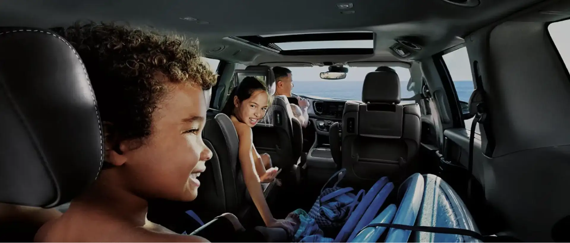 Family enjoying a coastal drive inside a Chrysler Pacifica
