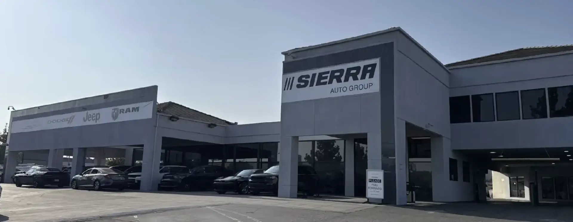 Exterior of the Sierra CDJR of Monrovia dealership, with Sierra Auto Group signage and Dodge, Jeep, and Ram vehicles parked out front