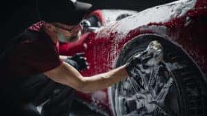 man washing tires of a sportscar