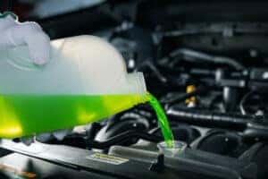 pouring antifreeze coolant liquid into car engine radiator