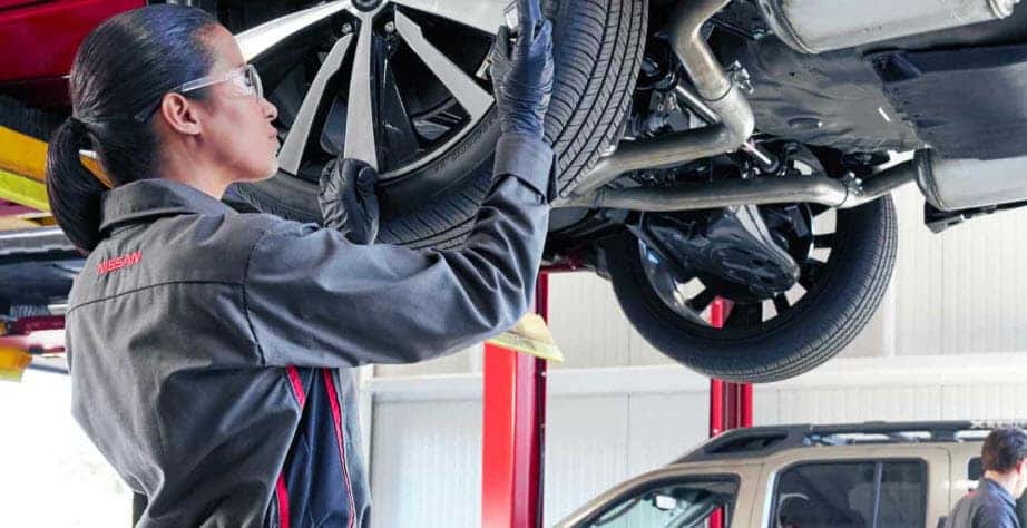 Nissan technician performing tire rotation service at Nissan of Vero Beach