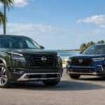 2026 Nissan Pathfinder parked next to Honda Pilot with palm trees in the background