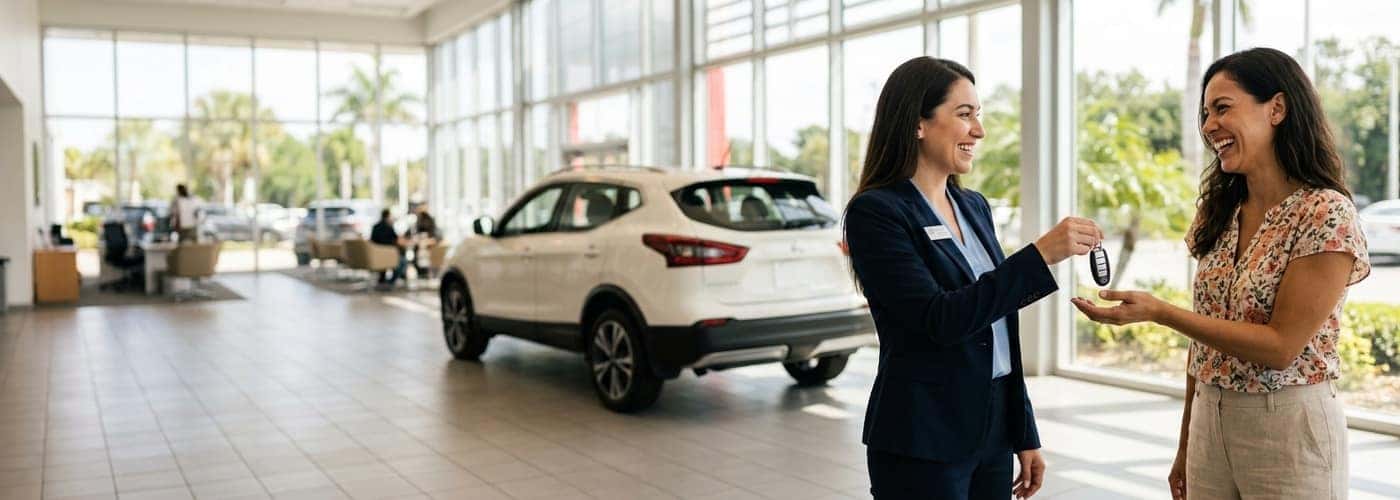 Smiling customer receiving car keys from a Nissan of Vero Beach associate in a bright showroom after bad credit car financing