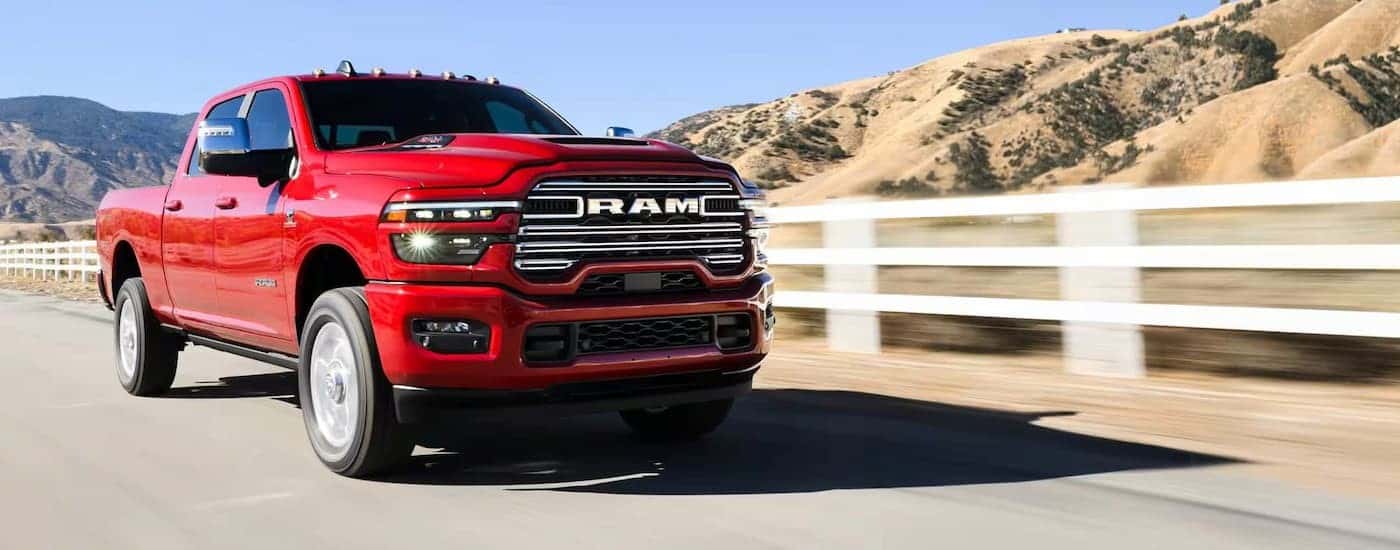 A red 2025 Ram 2500 driving to a Ram dealer near Lakehills.