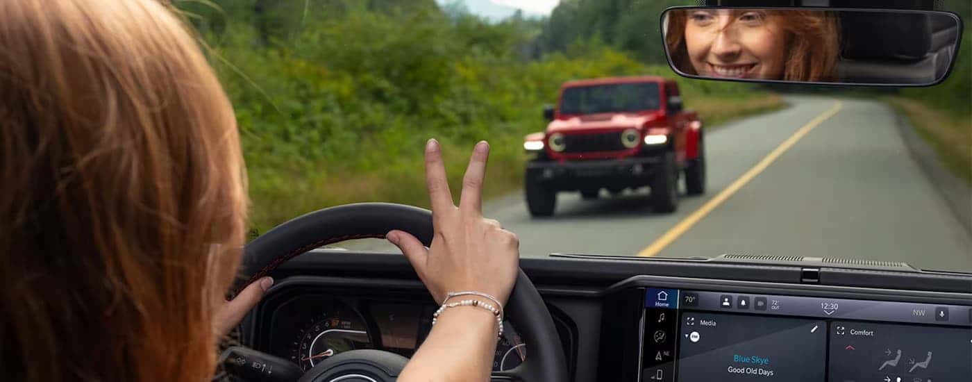 A woman is waving to another driver.