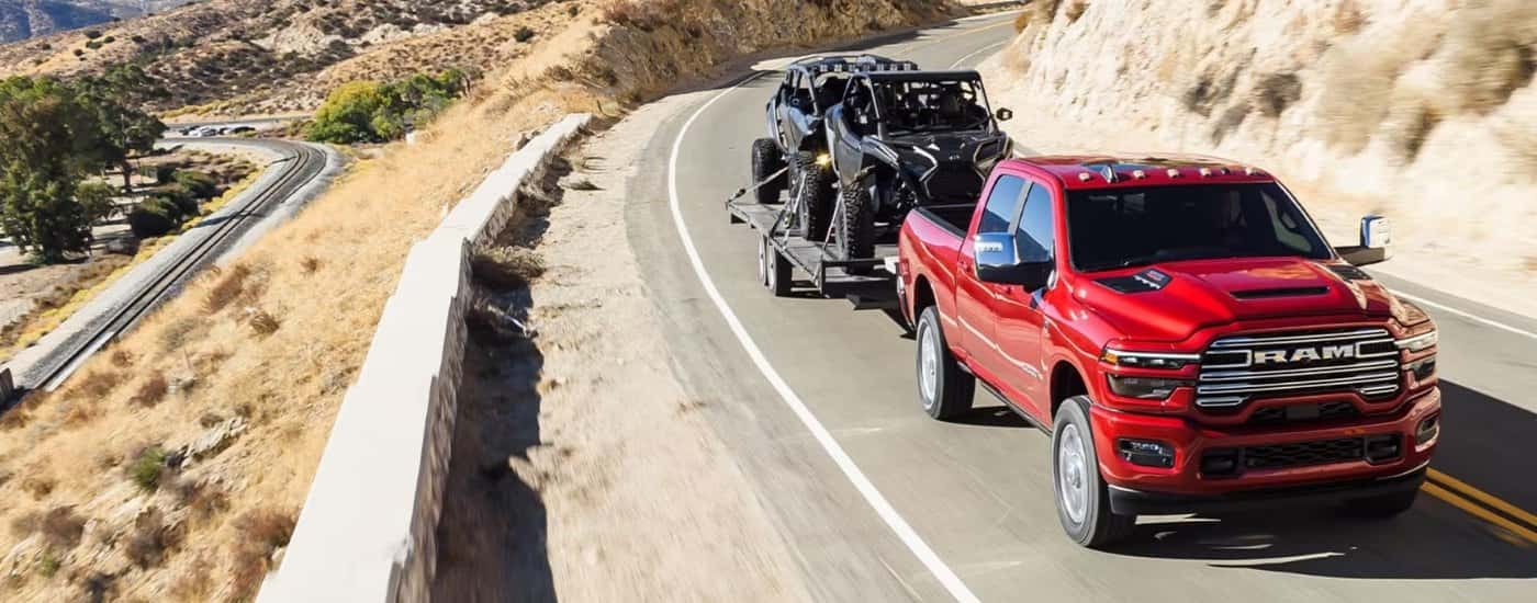 A red 2025 Ram 2500 towing ATVs to a Ram dealer near Leon Valley.