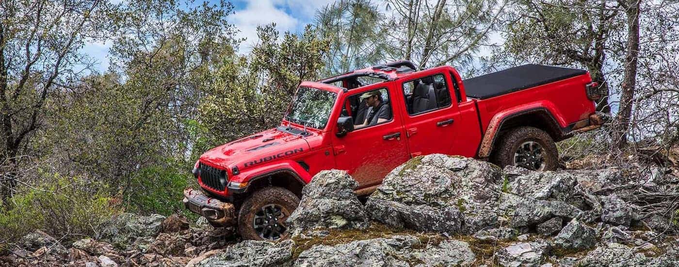 Red 2025 Jeep Gladiator Rubicon off-roading on rocks