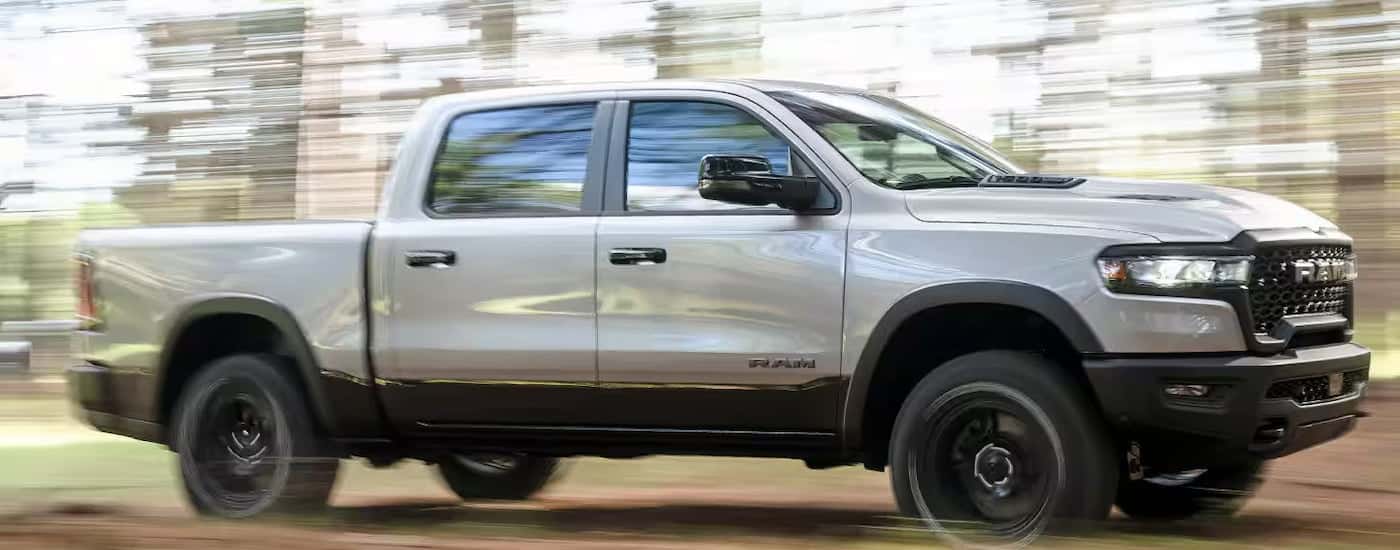 White 2024 Ram 1500 driving through a forest.
