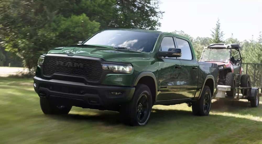 A green 2026 Ram 1500 Rebel towing a trailer.