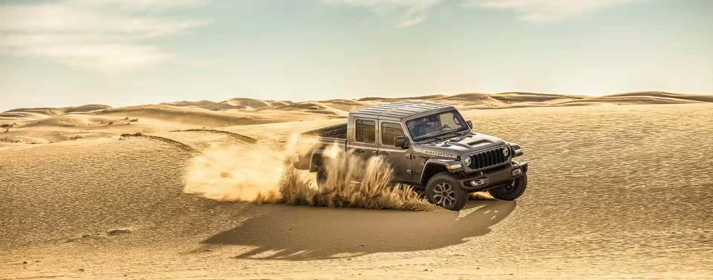Grey 2025 Jeep Gladiator Mojave X driving on sand dunes