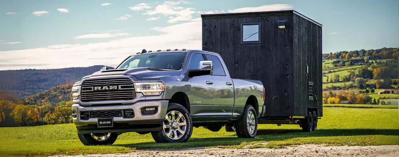 A gray 2023 Ram 2500 towing a small building