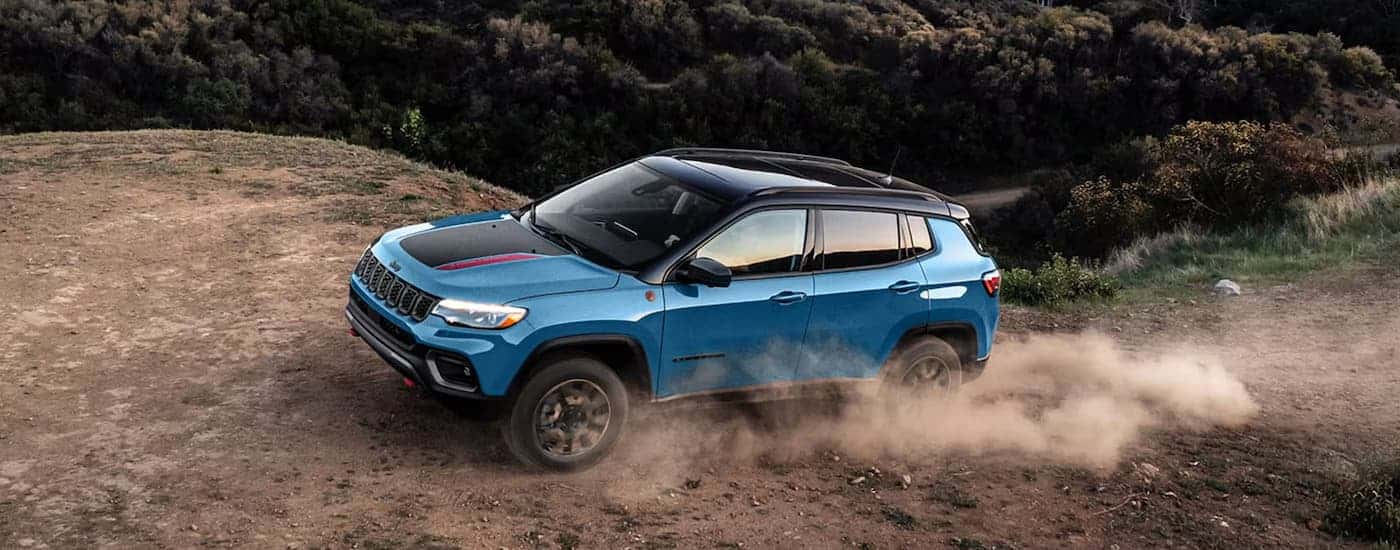 A blue 2026 Jeep Compass off-roading on a dirt trail