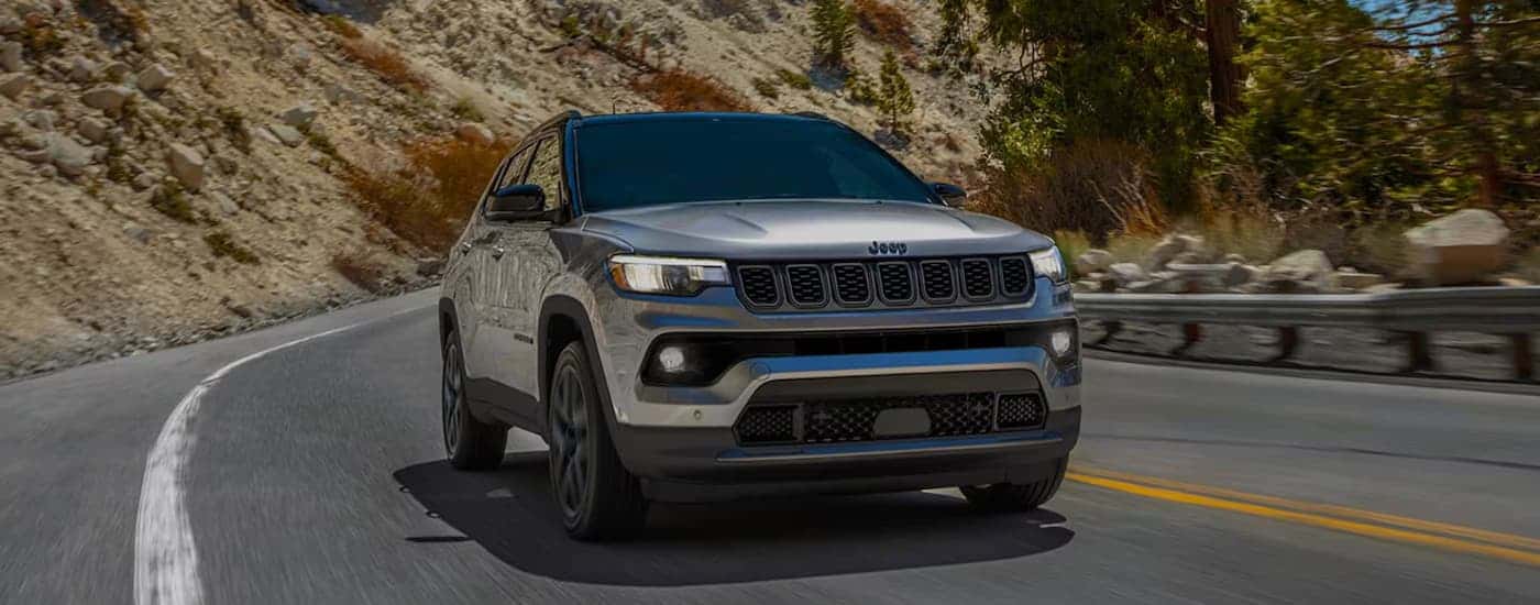 A silver 2026 Jeep Compass driving down a highway
