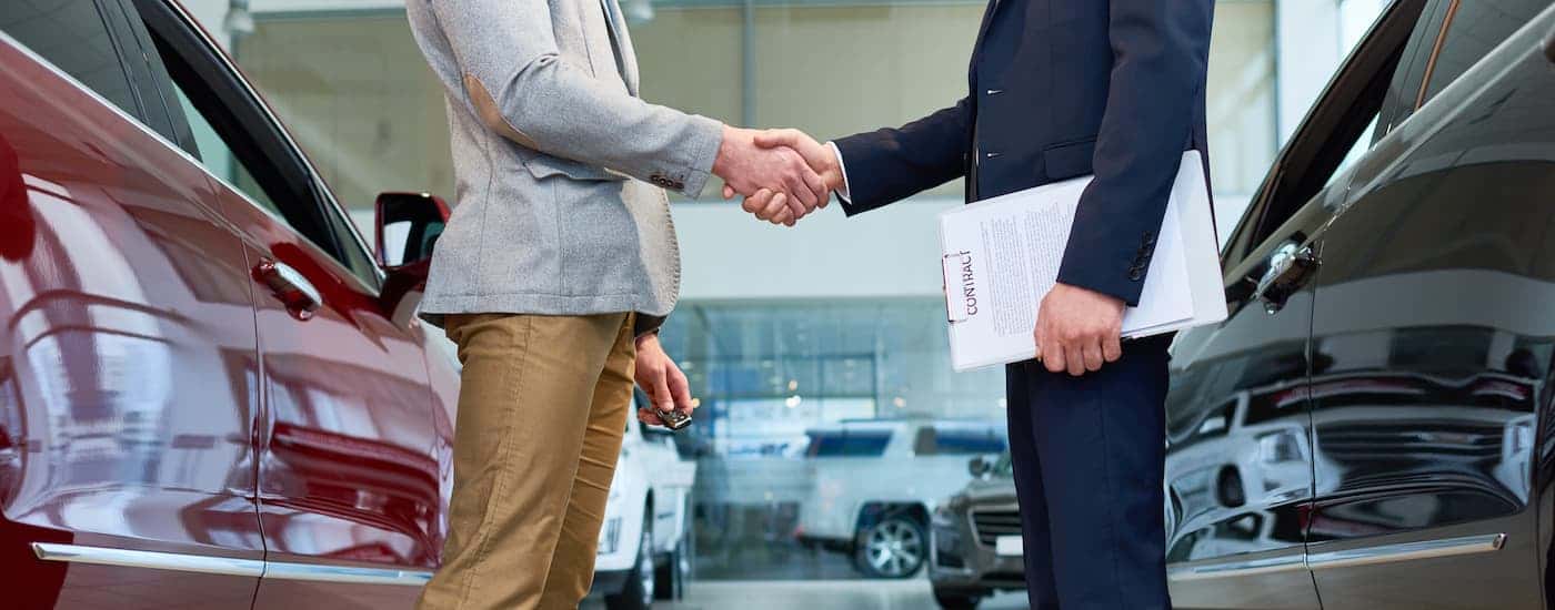 People shaking hands at a car dealership