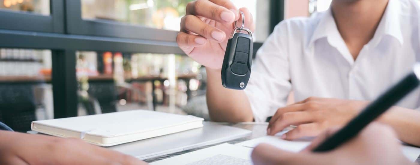 Person handing a keyfob to someone signing paperwork
