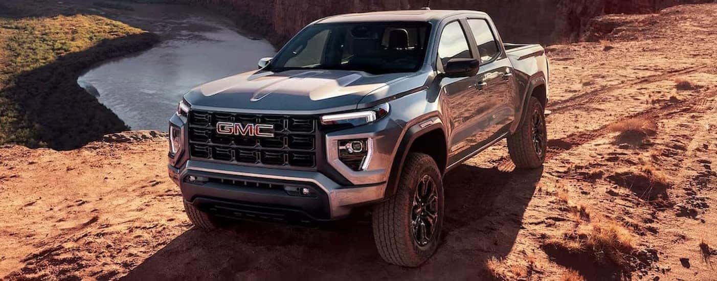 A blue 2024 GMC Canyon is shown parked off-road.