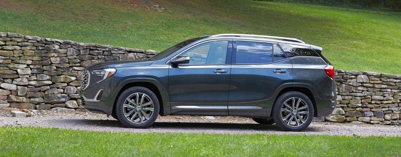 A blue 2018 GMC Terrain Denali is shown next to a rock wall.