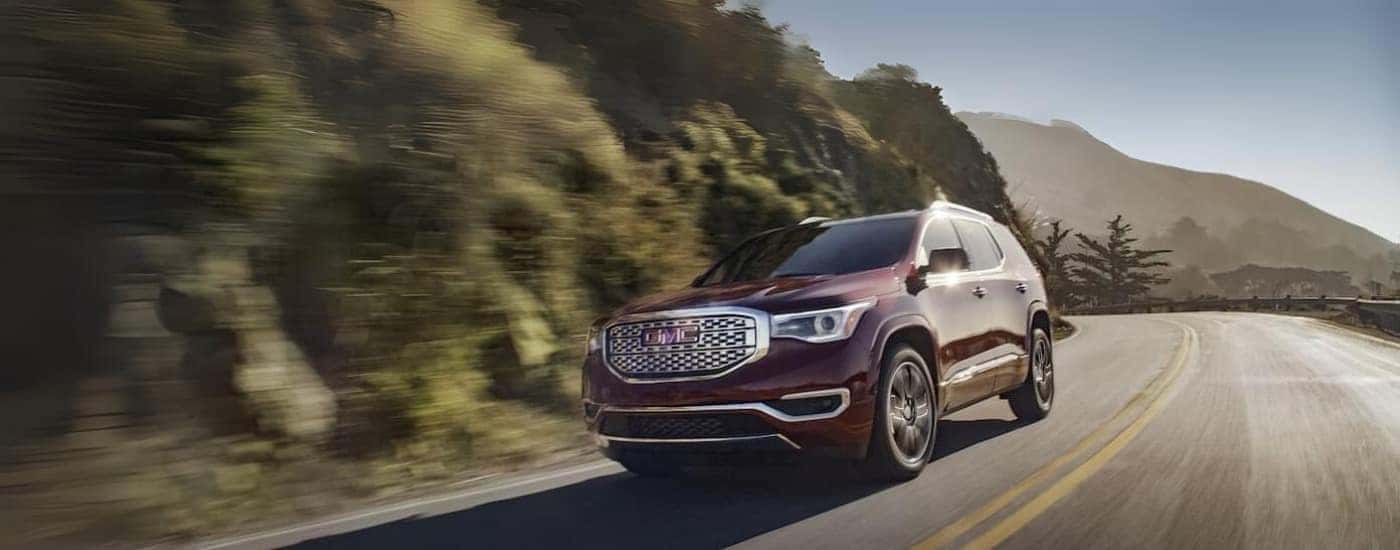 A purple 2019 GMC Acadia is shown driving to a used car dealer near Greensboro.