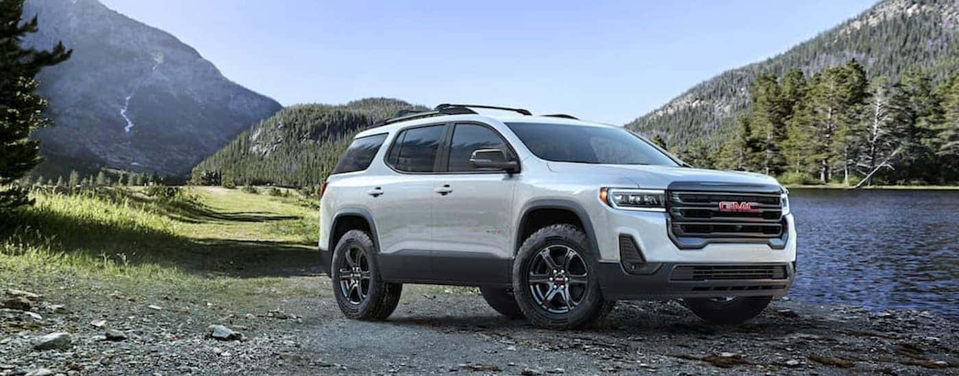 A white 2023 GMC Acadia AT4 is shown parked near a lake.
