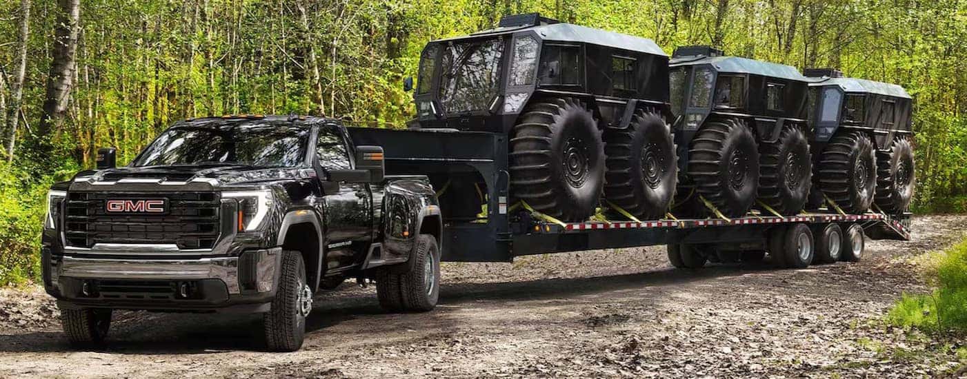 A black 2025 GMC Sierra 2500 for sale is shown towing three Sherps.