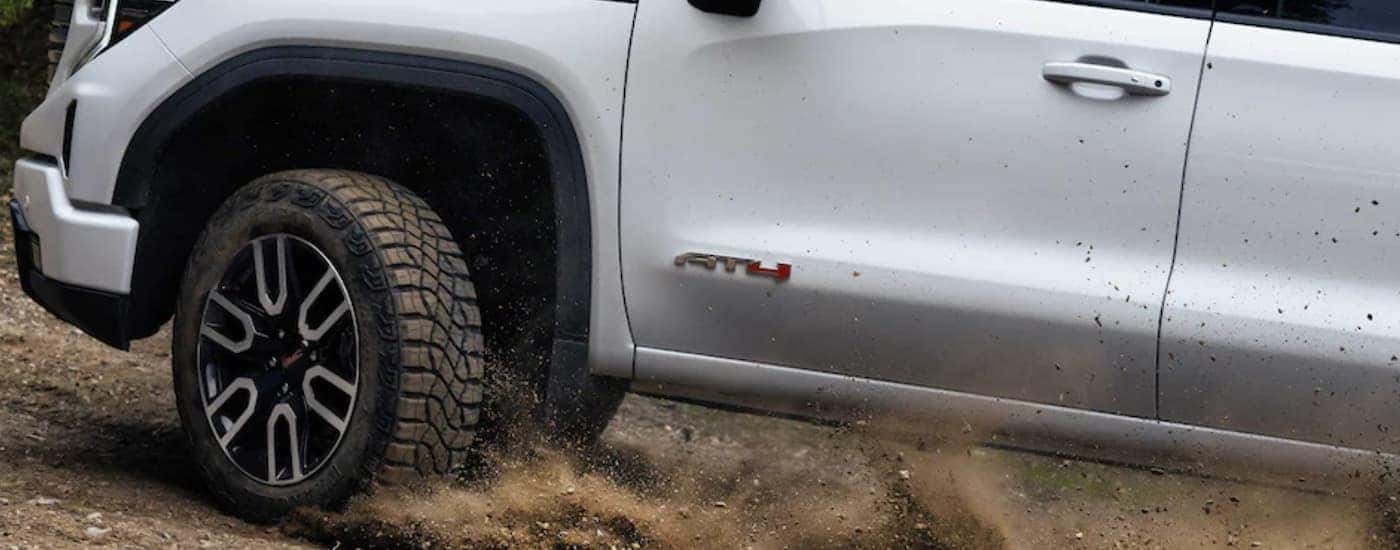 Close-up on the wheels of a white 2024 GMC Sierra 2500 HD AT4 driving off-road.