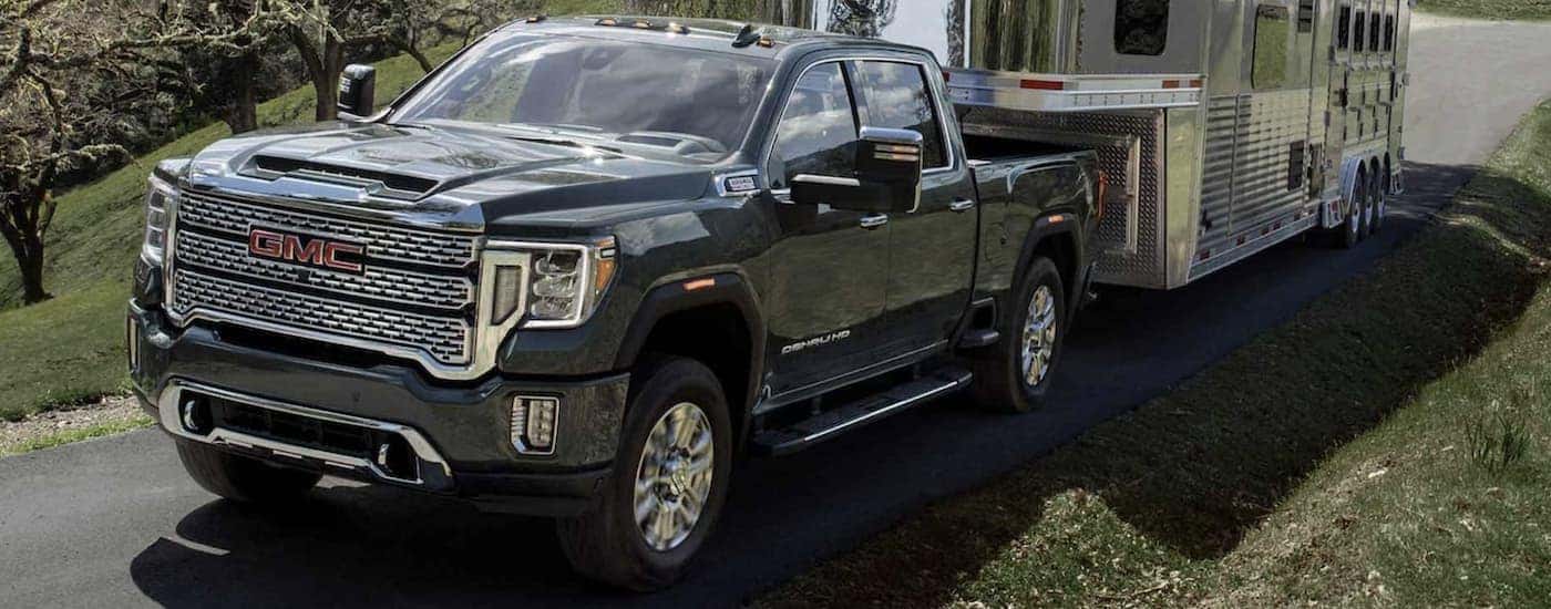 A black 2024 GMC Sierra 3500 HD towing a trailer from a dealer with a GMC Sierra for sale.