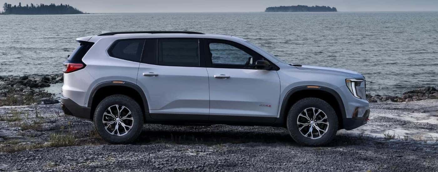 A white 2024 GMC Acadia is parked on a shore.