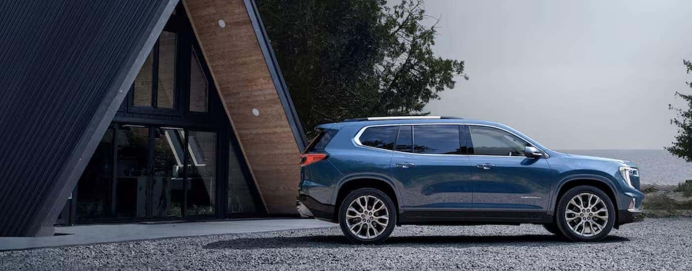 A blue 2025 GMC Acadia for sale near Greensboro is shown parked near a lake.