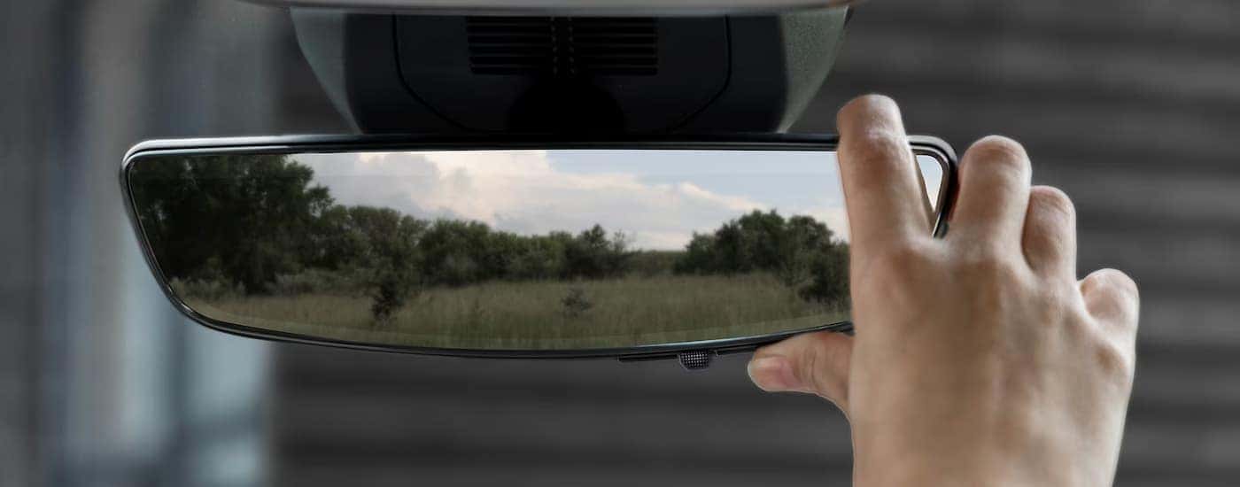 A hand is adjusting the rearview mirror in a 2025 GMC Terrain.