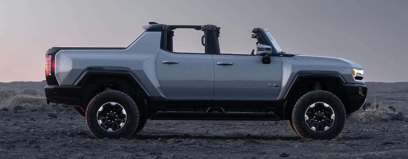 A silver 2025 GMC Hummer EV Pickup parked off-road.