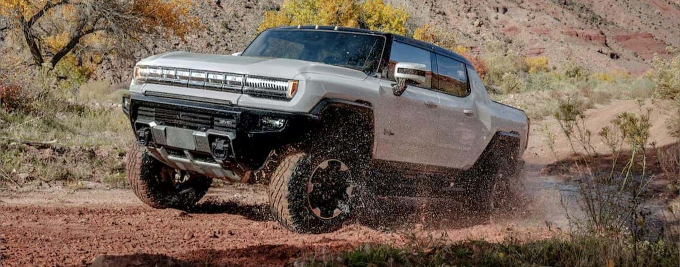 A white 2024 GMC Hummer EV pickup off-roading.