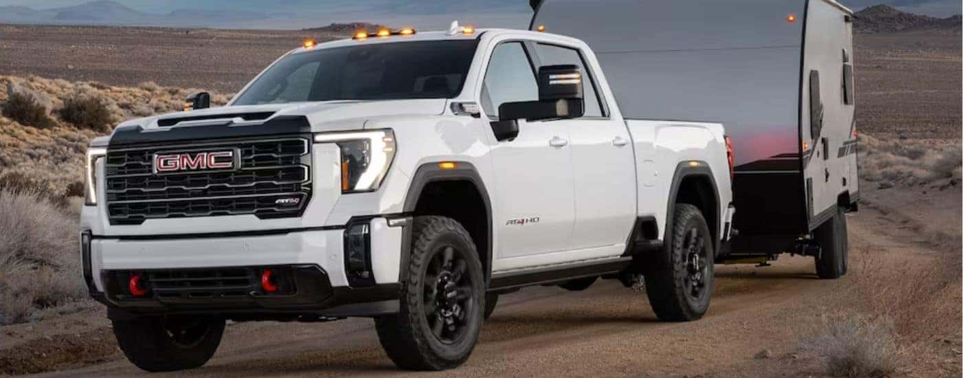 A white 2024 GMC Sierra 2500 HD towing a trailer.