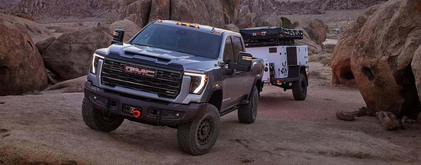 A gray 2025 GMC Sierra 2500 AT4X towing a trailer off-road.