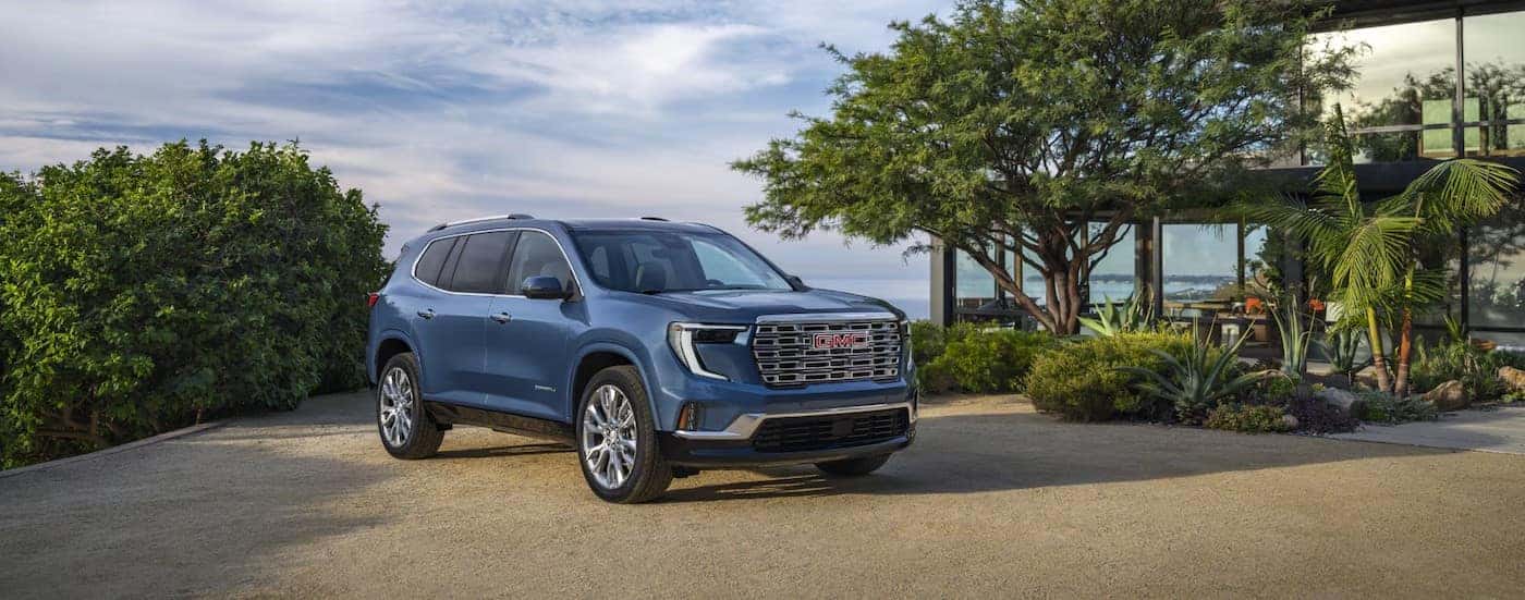 A blue 2025 GMC Acadia Denali parked on a driveway.