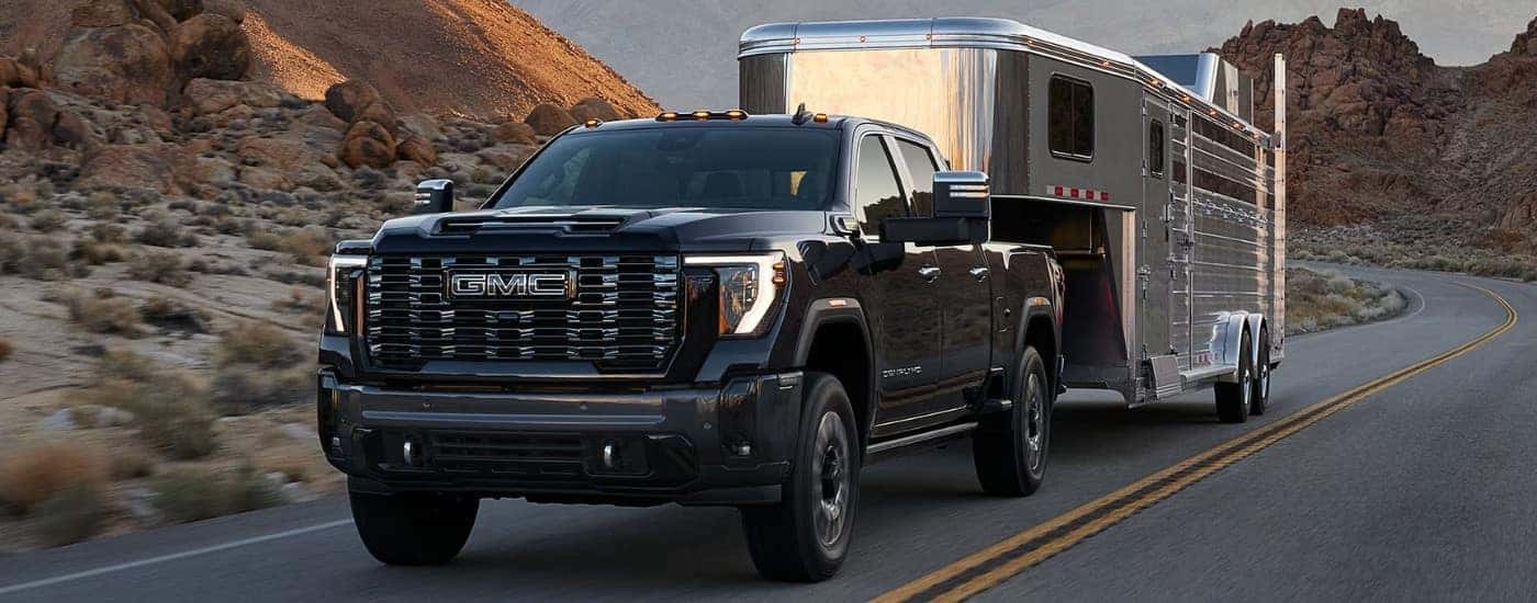 A white 2025 GMC Sierra 2500 HD Denali towing a trailer to a GMC dealer near High Point.