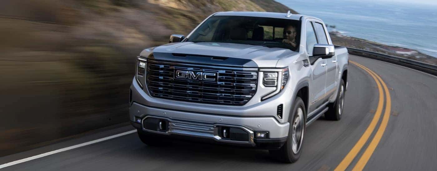 A silver 2024 GMC Sierra 1500 is shown driving to visit a GMC dealer near Winston-Salem.