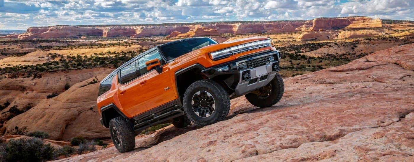An orange 2025 GMC Hummer EV for sale near me from the side.