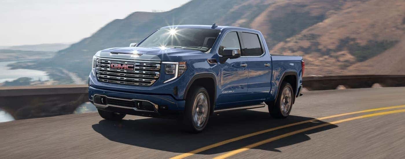 A blue 2025 GMC Sierra 1500 for sale in Kernersville driving on an open road.