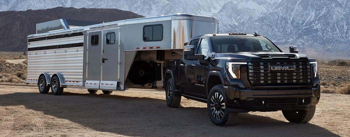A black 2025 GMC Sierra 2500 HD Denali towing a trailer.