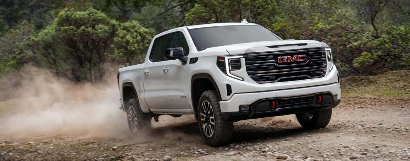 A white 2023 GMC Sierra 1500 driving on a trail.