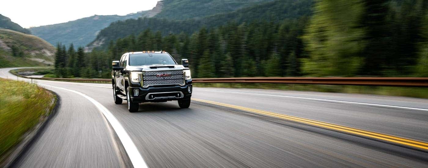 A black 2020 GMC Sierra 2500 HD Denali driving on a winding road.