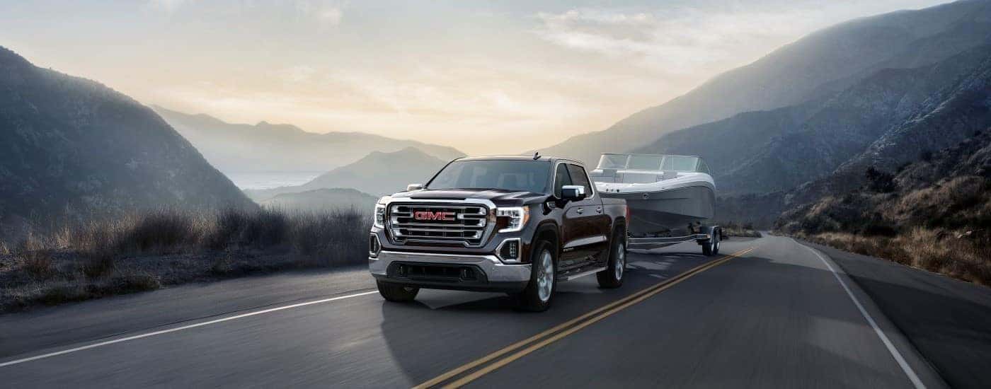 A black 2019 GMC Sierra 1500 SLT is shown towing a a boat to a used car dealer near High Point.
