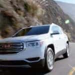 A white 2019 used GMC Acadia for sale rounding a corner.