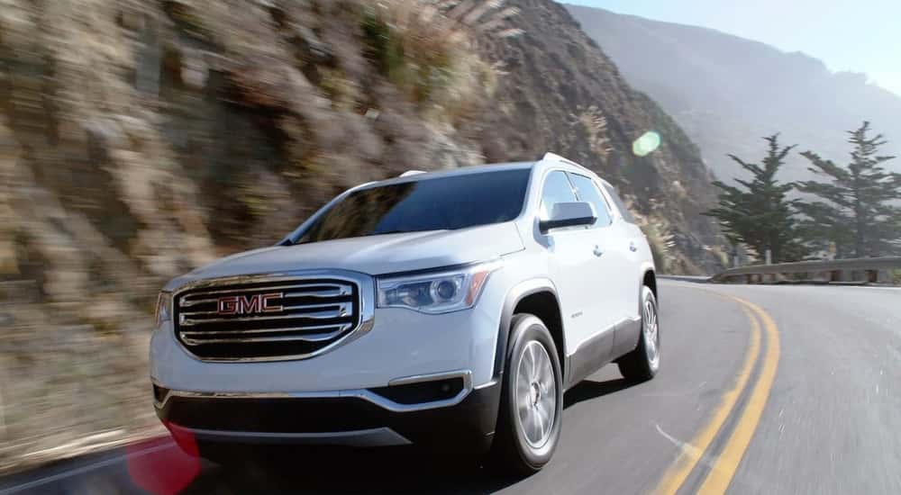 A white 2019 used GMC Acadia for sale rounding a corner.