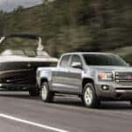 A silver 2019 GMC Canyon towing a boat.