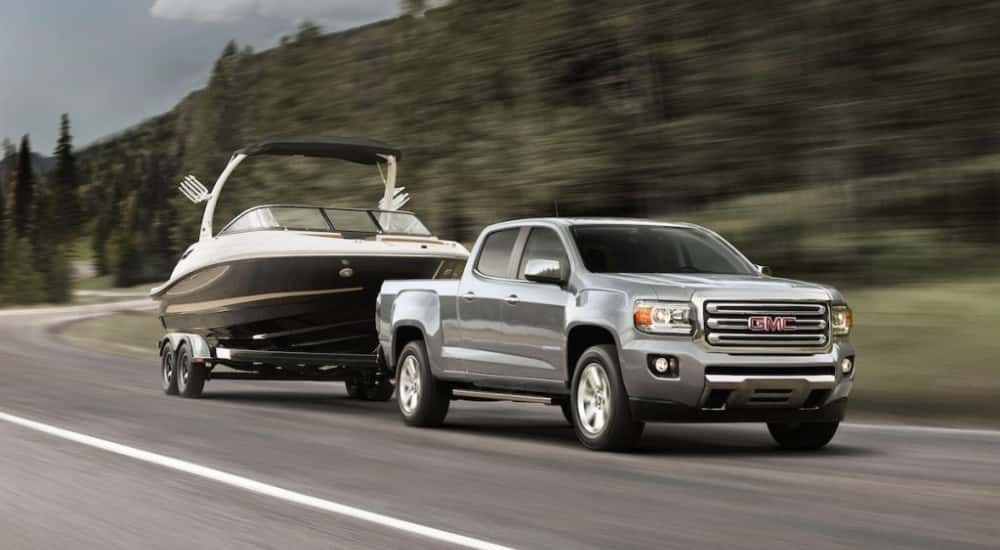 A silver 2019 GMC Canyon towing a boat.